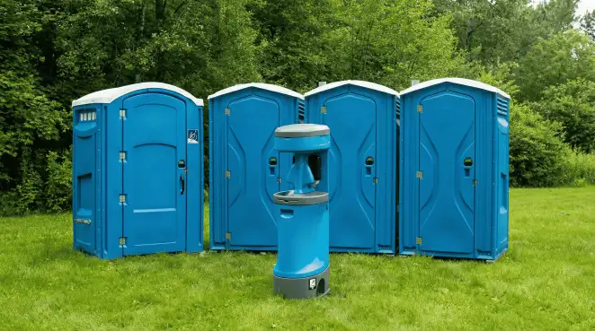 Four blue portable toilets and a matching hand washing station on grass near trees, a common sight at local outdoor events in Fort Collins, CO
